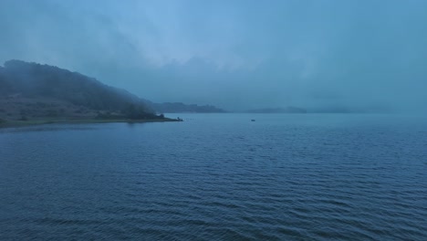 Mañana-Brumosa-En-El-Lago-Nanclares-De-Gamboa,-País-Vasco,-Con-Aguas-Serenas-Y-Sutiles-Rayos-De-Sol.