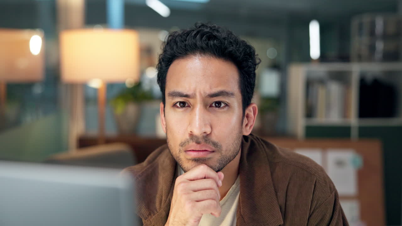 Thoughtful Young Man Working on Computer in Office