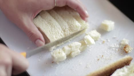 cutting bread into small cubes with a knife