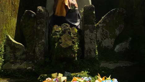 Tiro-Inclinado-En-Cámara-Lenta-De-Una-Piedra-Conmemorativa-Con-Ofrendas-Para-Una-Ceremonia-Hindú-El-Canang-Sari-Como-Signo-De-Gratitud-En-Bali-En-Indonesia