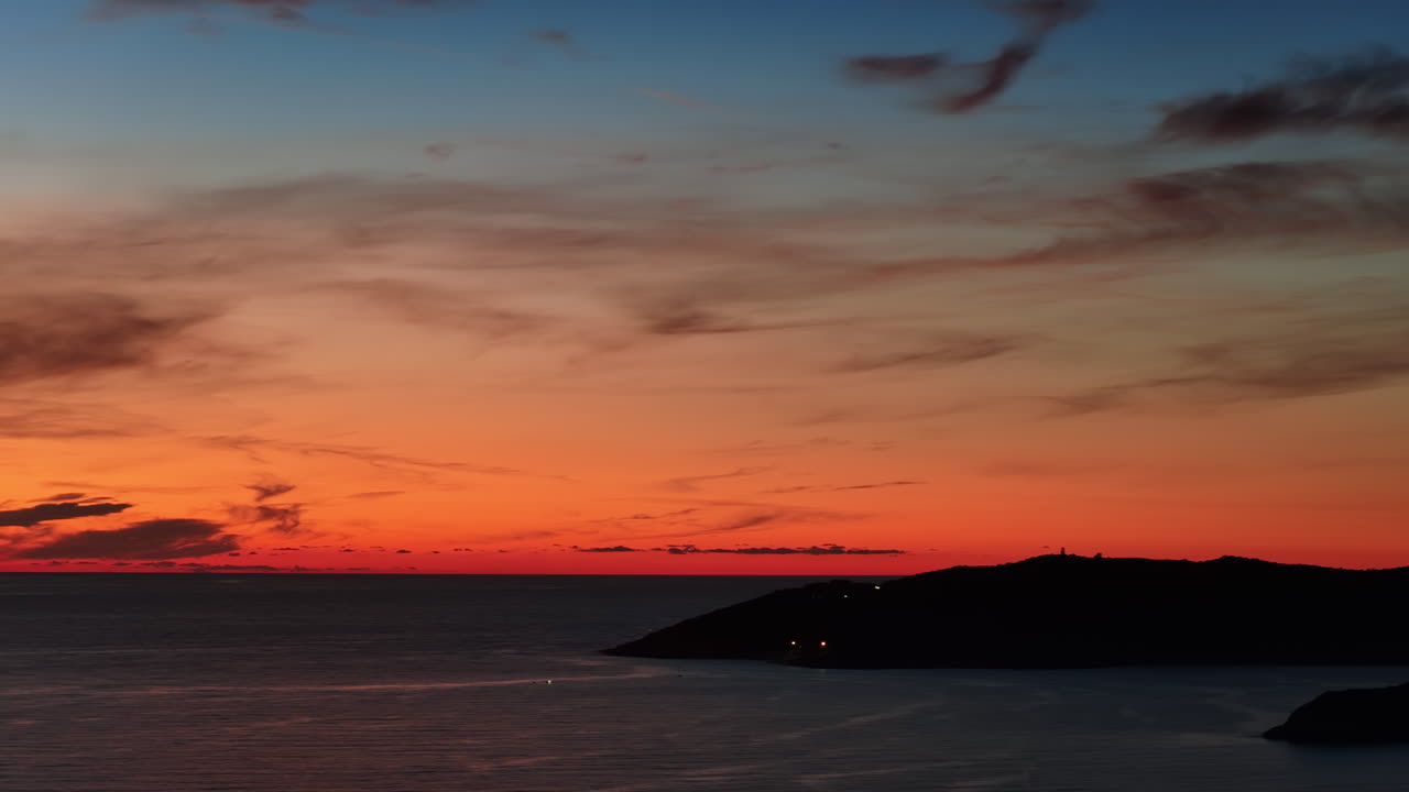 穏やかな海に沈む鮮やかな夕日の空撮ドローン映像。暖かいオレンジ色と赤色が地平線全体に輝いています。モンテネグロ。