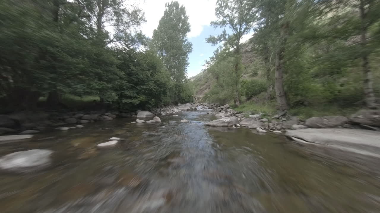 Drone aereo sportivo FPV veloce che vola basso sul corso d'acqua naturale di un fiume di montagna