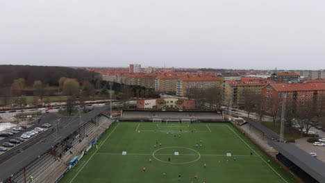 aerial tilt down ascending over people training on soccer field at malmo stadium, sweden