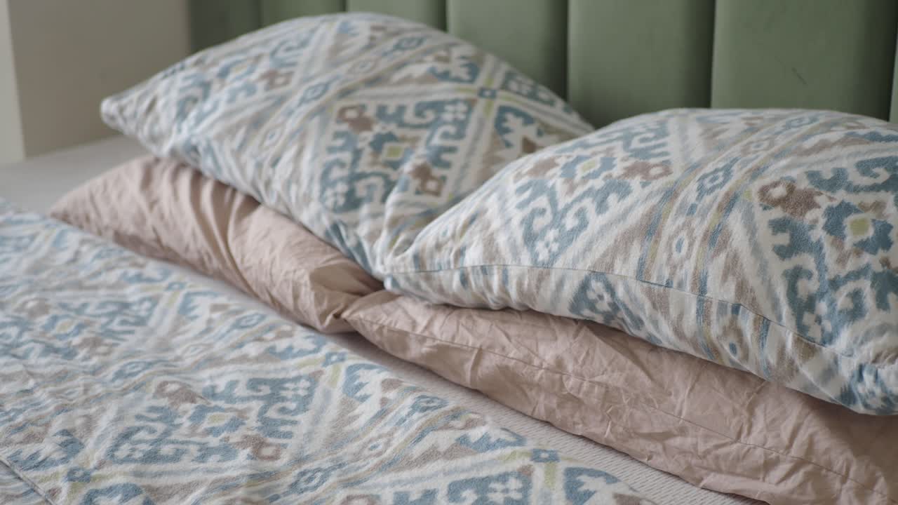 Primo piano di un letto con cuscini a fantasia e piumone.