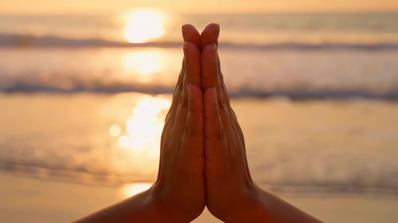Due mani premute palmo contro palmo con le punte delle dita allineate accanto all'acqua luminosa del tramonto su una spiaggia tranquilla, che riflette una luce calda, sfocatura morbida dell'orizzonte, atmosfera pacifica, consapevolezza e gratitudine.