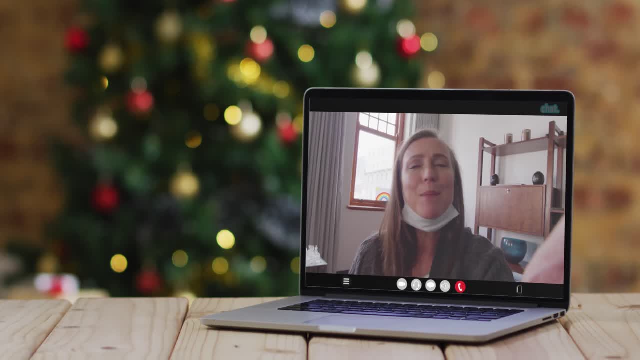 feliz mujer mayor caucásica en videollamada en computadora portátil, con decoraciones de navidad y árbol