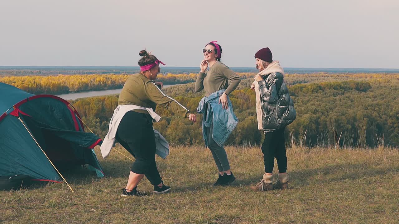 дамы прыгают и танцуют в красивой голубой палатке на фоне спокойной реки