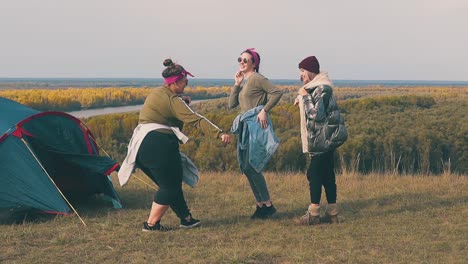 pretty ladies jump and dance at blue tent against calm river