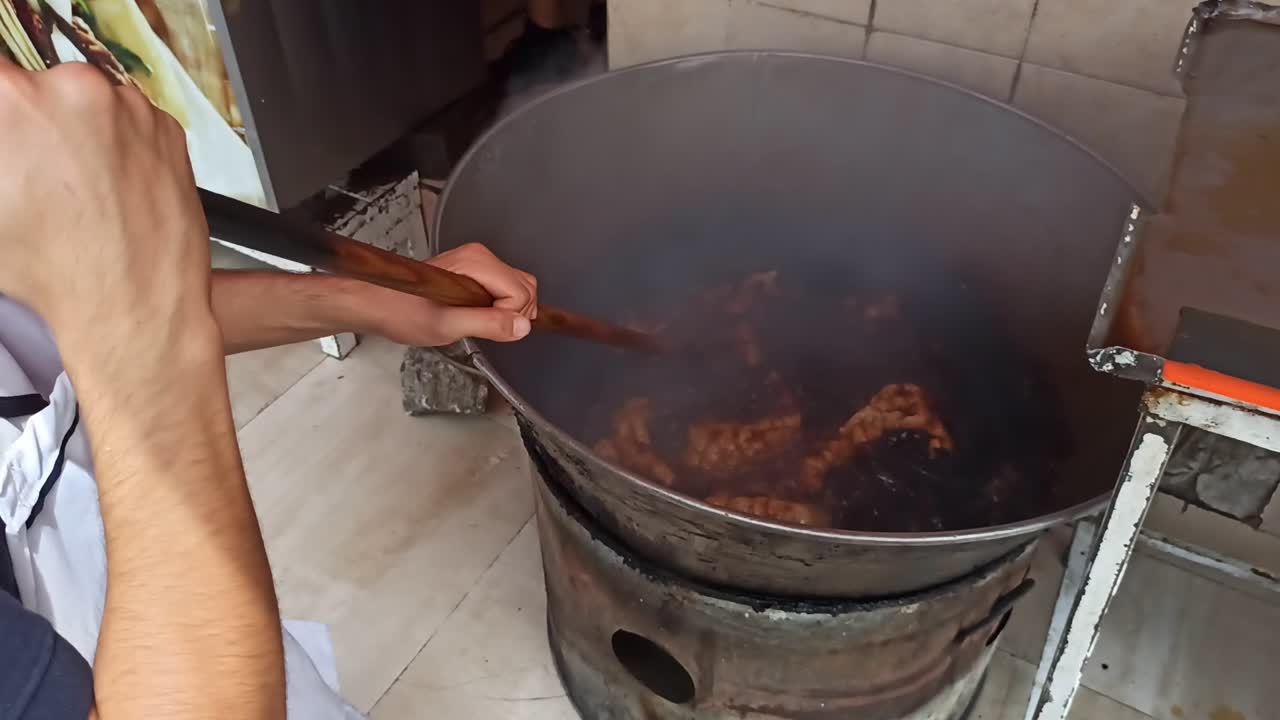 un hombre friendo piel de cerdo en aceite caliente