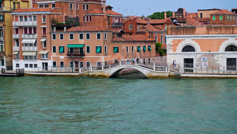 view of narrow canal with bridge in venice, italy - wide shot