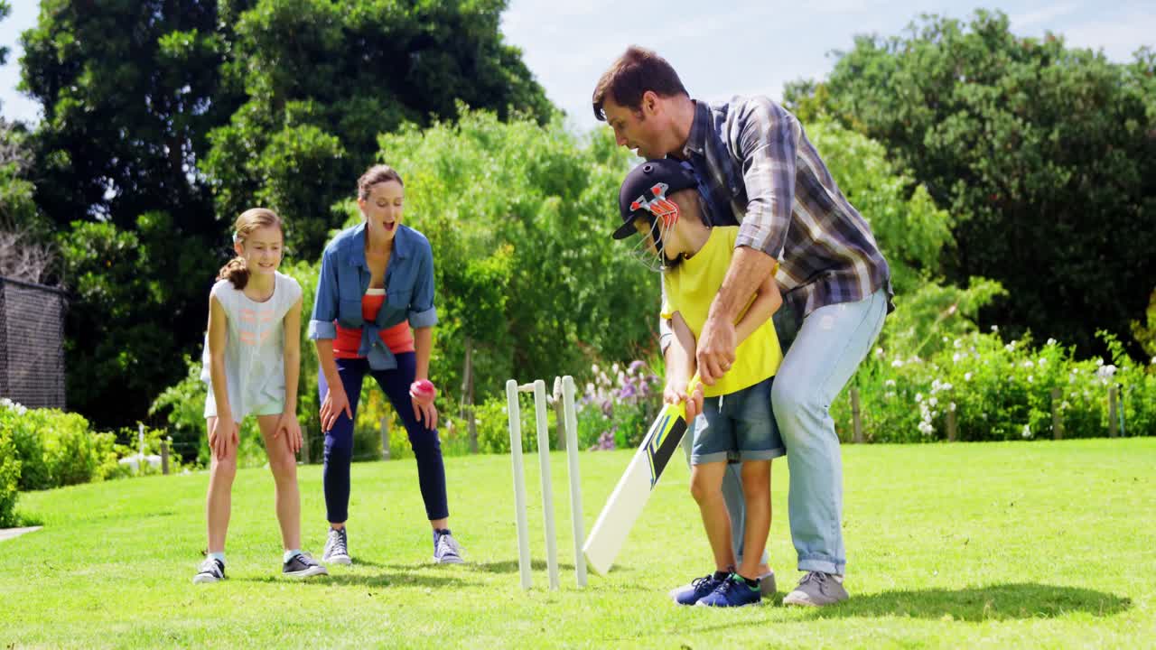 Familia jugando al cricket en el parque