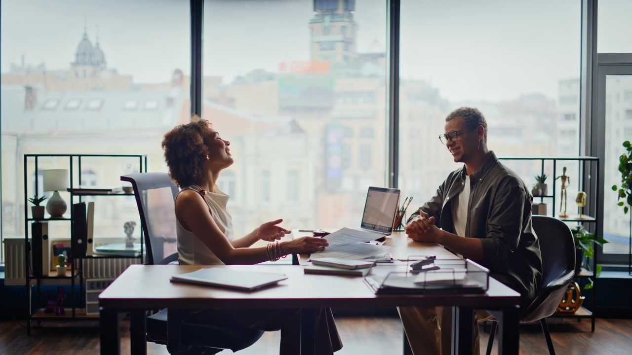 Homme et femme discutant de documents sur un bureau. Des collègues en réunion dans un bureau moderne.