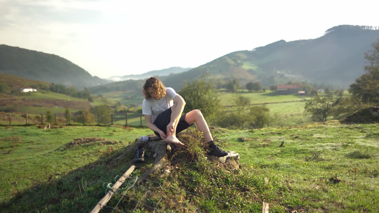 Wanderer klebt Pflaster und versorgt Blasen nach einer Naturwanderung.