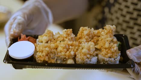 persona con guantes que sirve un plato fresco de sushi con salsa de soja