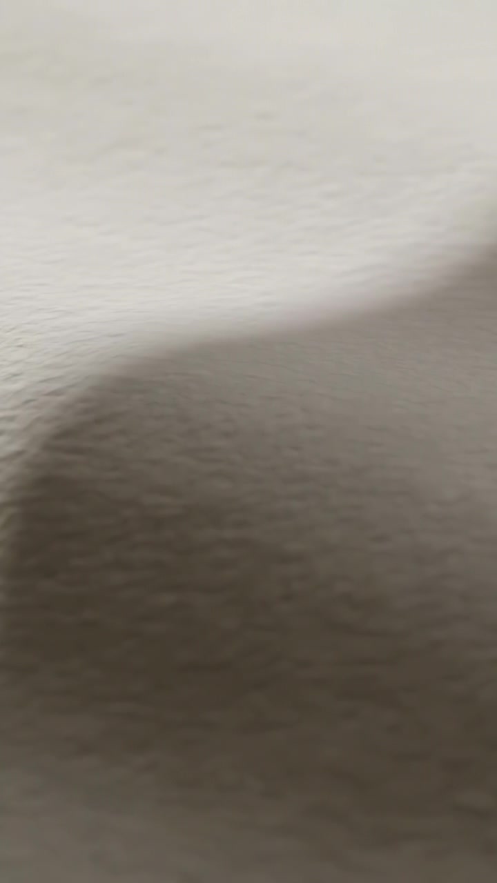 Video verticale: Ombra arrotondata che si sposta verso l'alto su una parete strutturata in una stanza a causa del movimento della luce.
