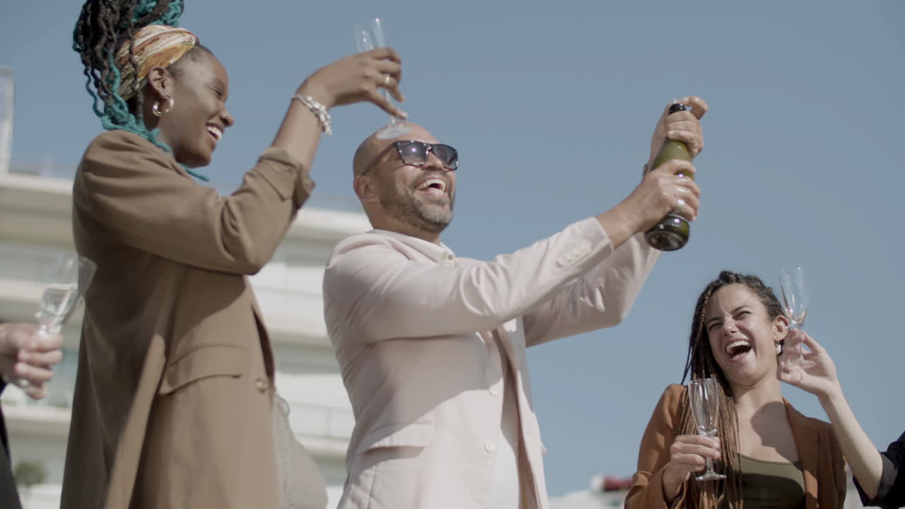 Happy employees opening champagne with splashes during party