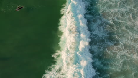 top view of surfers on splashing foamy waves at llandudno beach in cape town, south africa