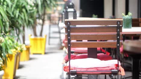 empty cafe tables with red cushions and plants