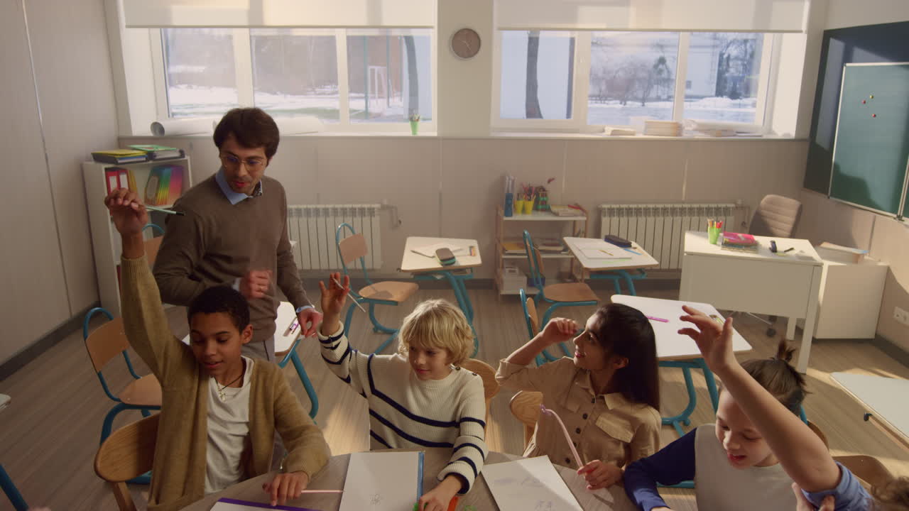 학생 들 이 교실 에서 수업 에 손 을 들고 있다. 학교 교사 가 질문 을 하고 있다