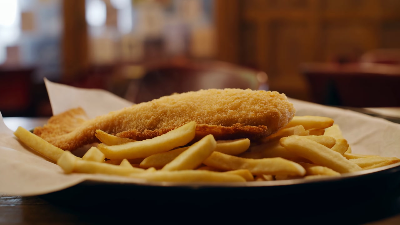 Golden Breaded Fish And Fries On Parchmentlined Plate In Woodpaneled Pub, Warm Ambient Lighting, Crunchy