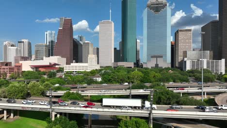 aerial reveal of downtown houston texas skyline as traffic rushes by on interstate freeway highways