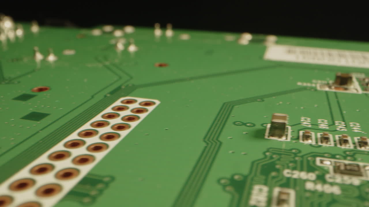 Detailed macro dolly of connections and microchips on a green circuit board