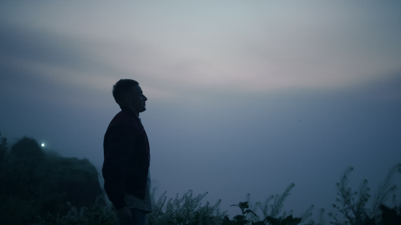 Uomo in piedi sul bordo della montagna all'alba. Uomo eccitato che alza le mani in aria.