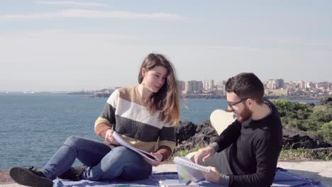 students sitting learning and studying for exams near the sea