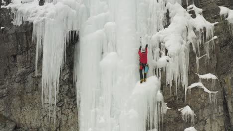 mountain climber on frozen cascade progressing towards peak