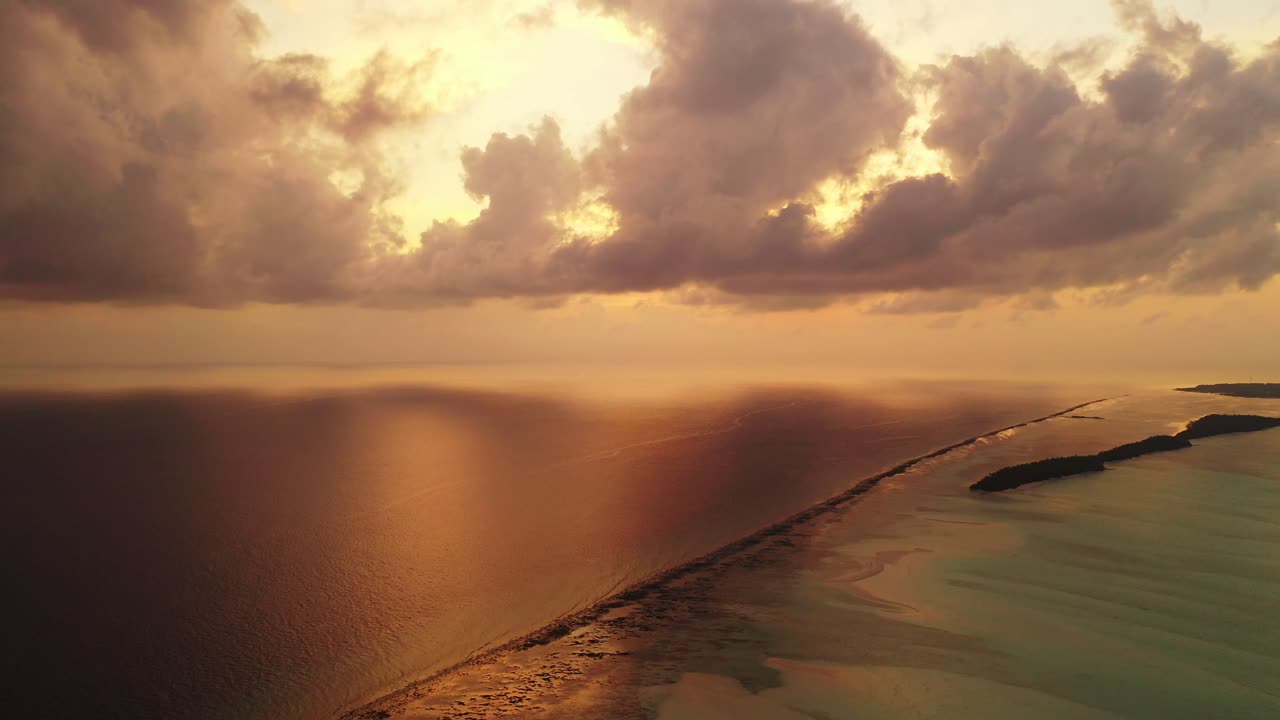 Stormy heavy clouds above the calm ocean and coral reef. Sunrise above the sea