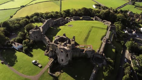 Historic-Welsh-landmark-Denbigh-Castle-medieval-old-hill-monument-ruin-tourist-attraction-aerial-high-orbit-left-top-down-view