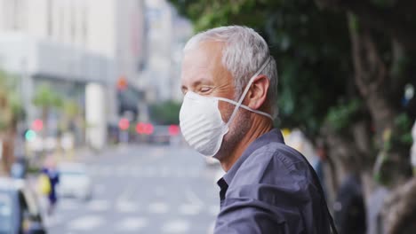 caucasian man out and about in the street wearing on a face mask against coronavirus