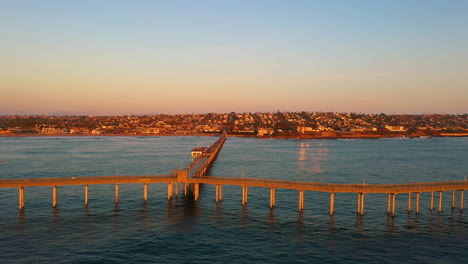 Puesta-De-Sol-Sobre-El-Muelle-De-La-Playa-Del-Océano,-San-Diego,-California,-Drone-De-Lado