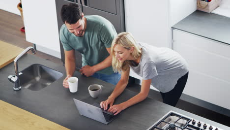Overhead-View-Of-Couple-Looking-At-Laptop-In-Modern-Kitchen