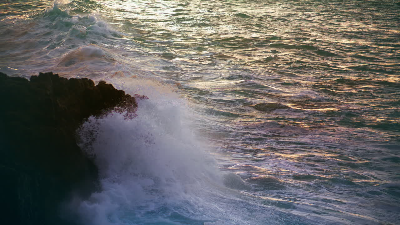 las olas blancas golpean las rocas por la noche. el océano tormentoso rompe la playa del volcán.