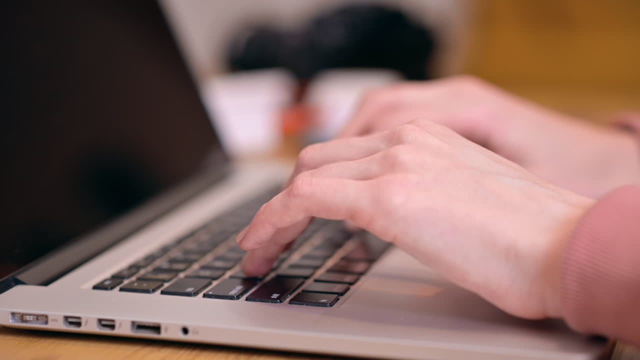Female hands typing on laptop with headphones on background. Working from home