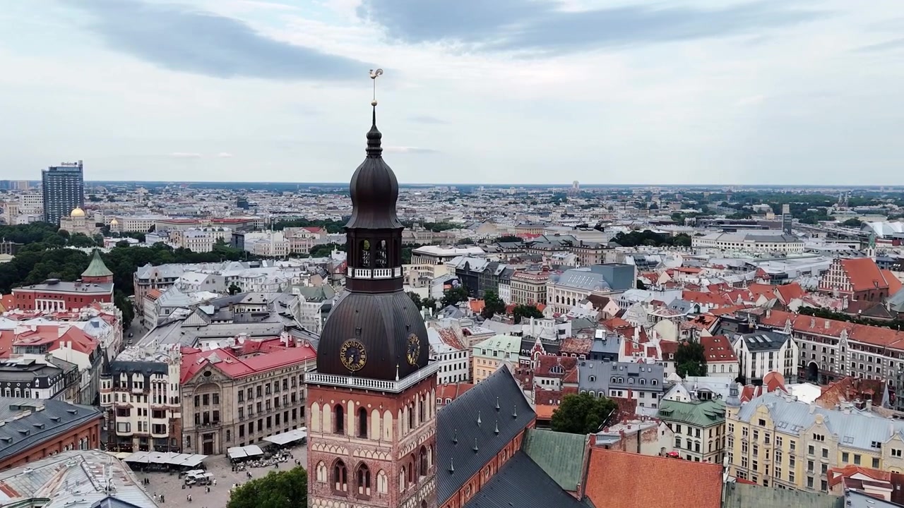 La Cattedrale di Riga si erge nel mezzo dei tetti compatti della Città Vecchia mentre la telecamera vola lentamente in avanti sopra la città