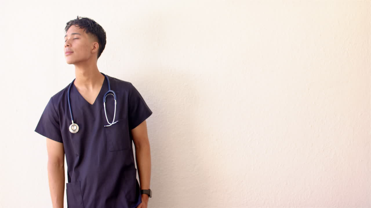 Standing confidently, male nurse in scrubs with stethoscope, copy space