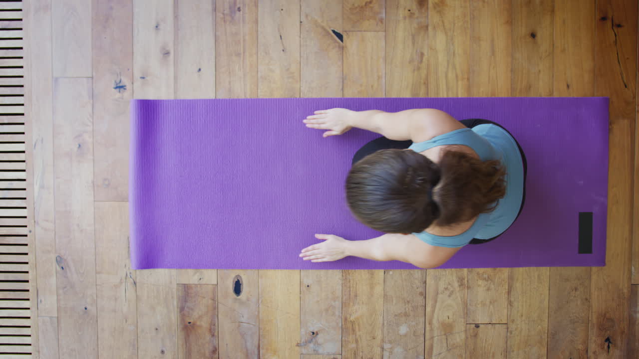vista aérea de una mujer joven haciendo yoga en el suelo de madera