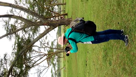 Vertical-shot-of-tourist-photographer-filming-wildlife-animals-in-Kenya,-day