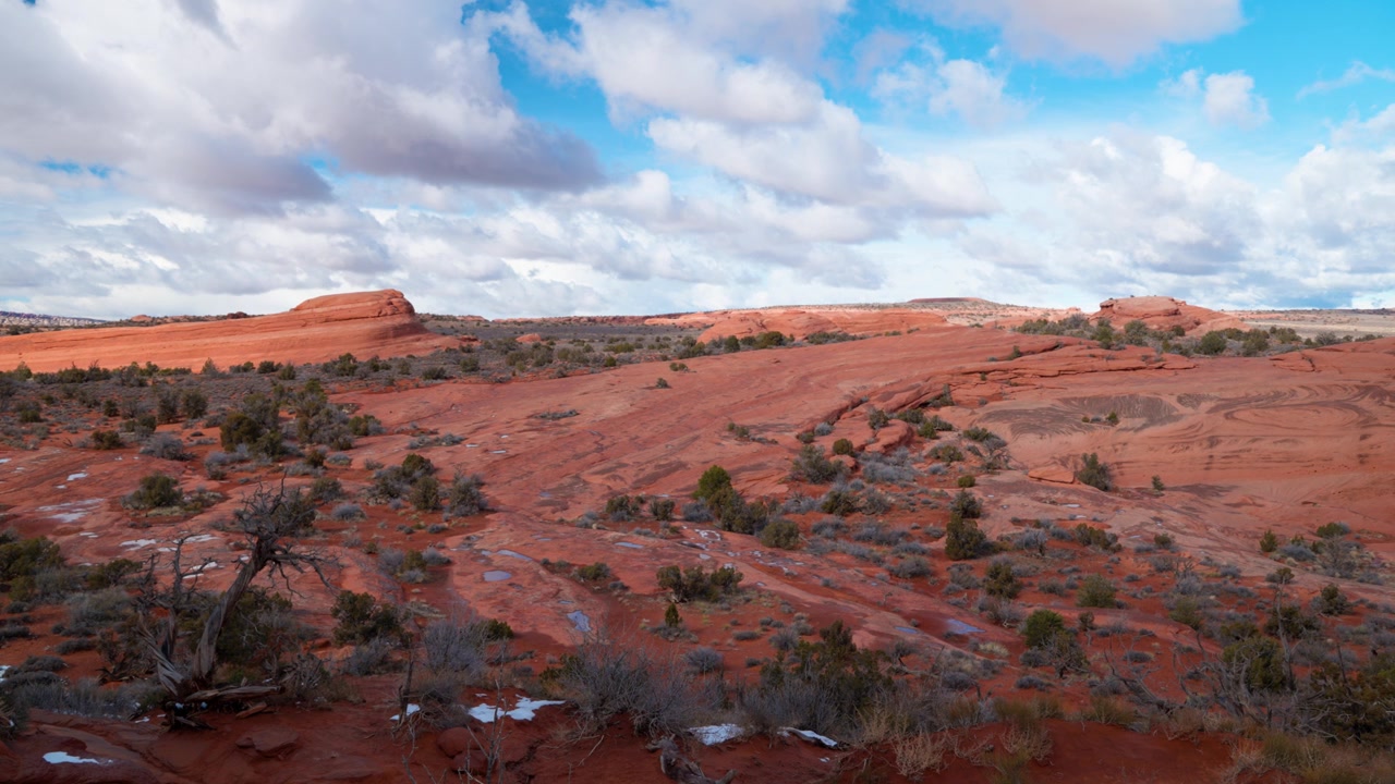 Statisch breedbeeld van een adembenemend rotslandschap met dikke wolken die voorbijtrekken en een levendige blauwe lucht, die de schoonheid van Utah's Arches National Park toont.