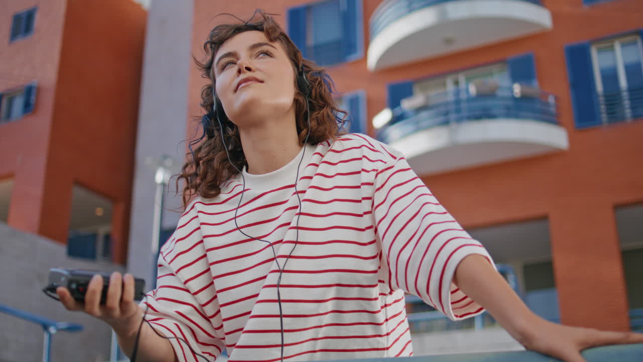 chica con un reproductor de cassette escuchando música en un área urbana sola de cerca.