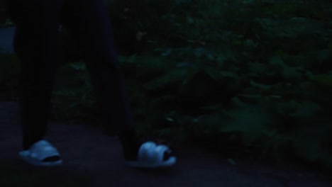 young asian woman walks to lake at sunrise, sits on bench with thermos