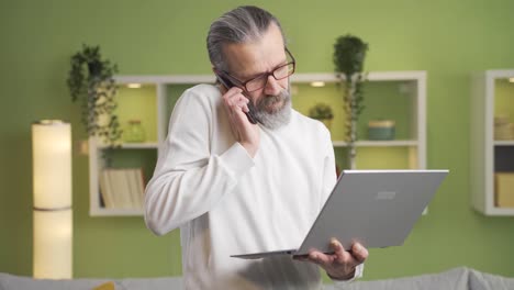 Mature-man-talks-on-the-phone-using-a-laptop-at-home.-Business-speech,-meeting,-brainstorming.