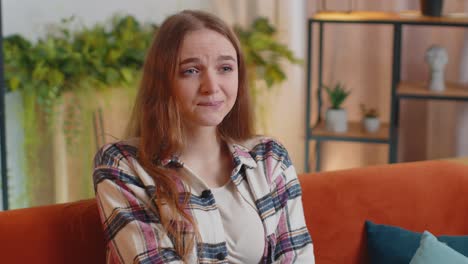 pretty girl alone at home having doubts no idea being clueless and uncertain shrugs shoulders