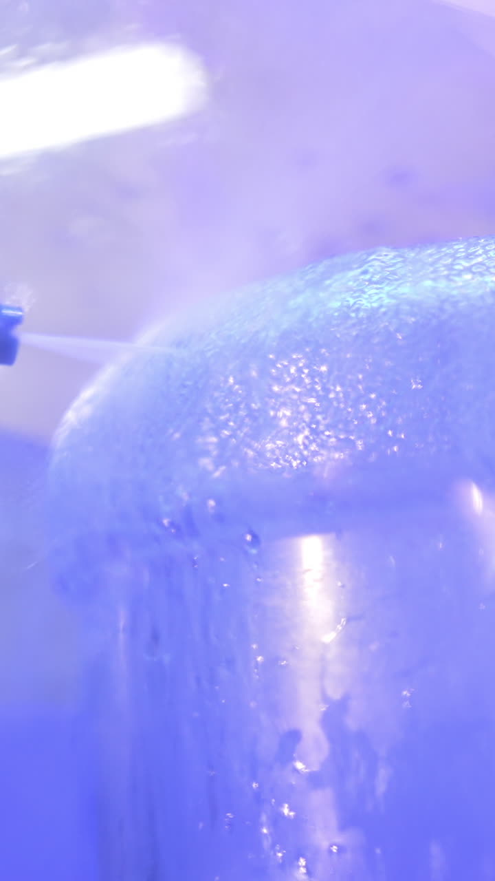 Packing materials for fresh water being washed and prepared for to be filled with water. Close up. Water in bottles production. Vertical video