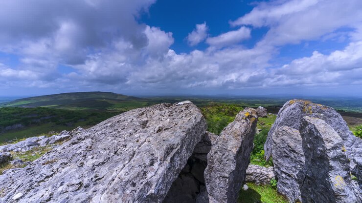 Timelapse di paesaggio rurale con formazione rocciosa neolitica in primo piano durante una giornata nuvolosa e soleggiata, visto da Carrowkeel nella contea di Sligo in Irlanda