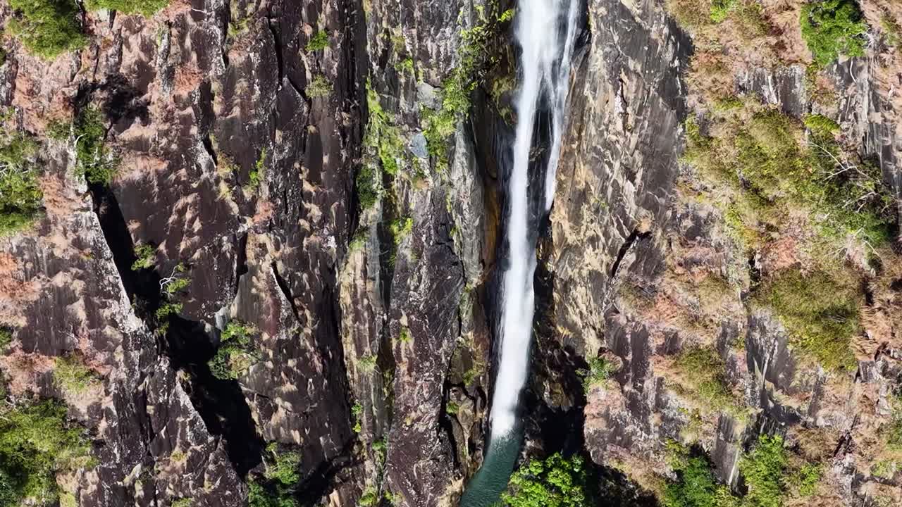 Un'immagine aerea ad angolazione elevata cattura una sottile cascata che scorre lungo una ripida parete rocciosa texturizzata