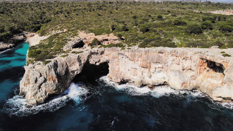 a drone shot panning around a large sea arch near cala varques in majorca