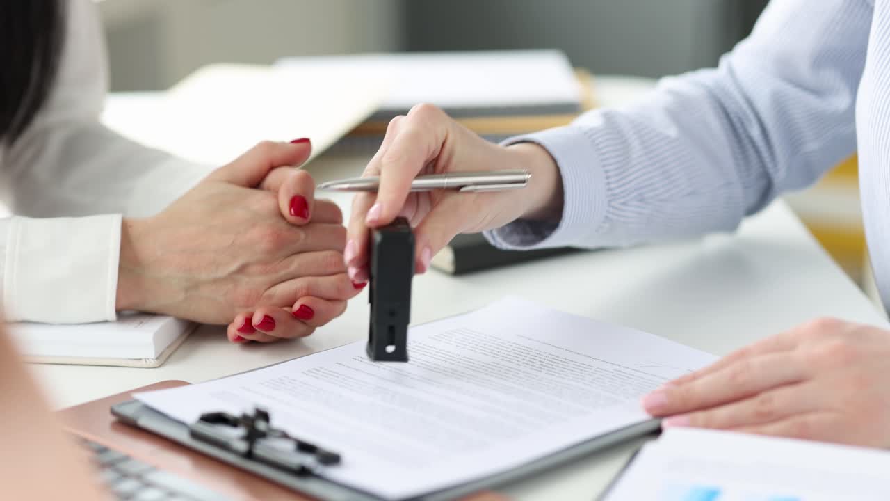 Donna firma un documento e appone un timbro in ufficio, filmato 4K